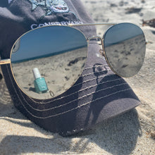 Load image into Gallery viewer, Round sunglasses with reflective lenses on a textured surface reflecting a teal nail polish bottle